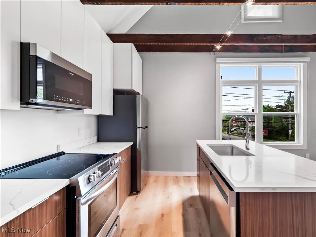 Kitchen with stainless steel appliances, modern cabinets, undermount sink, and light wood finished floors.