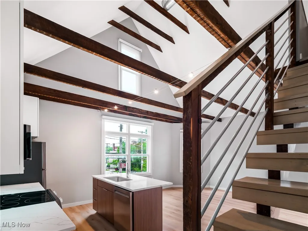 Stairs featuring beamed ceiling, wood finished floors, high vaulted ceiling, and baseboards