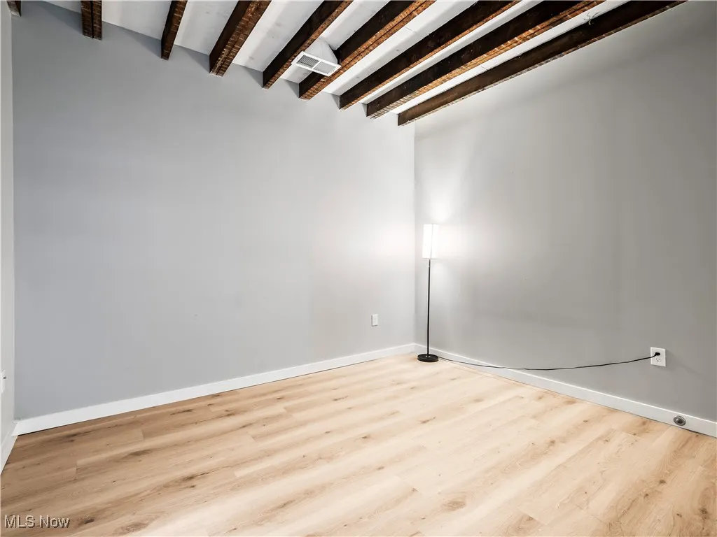 Bedroom featuring beam ceiling, wood finished floors, and baseboards