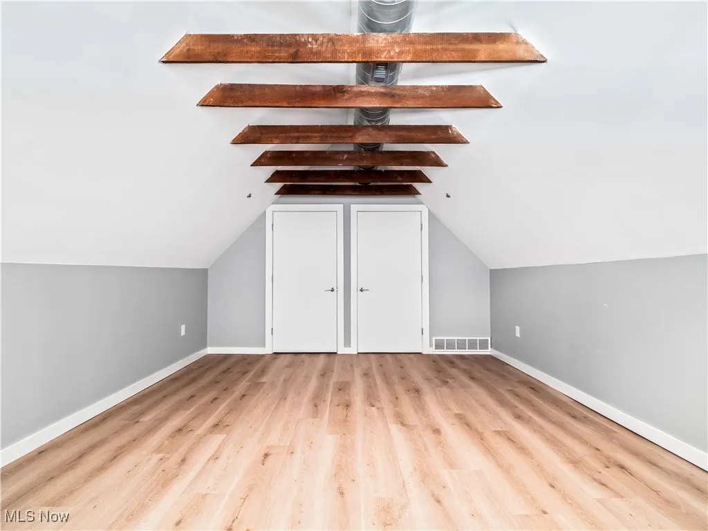 Bonus room/bedroom featuring wood finished floors and baseboards