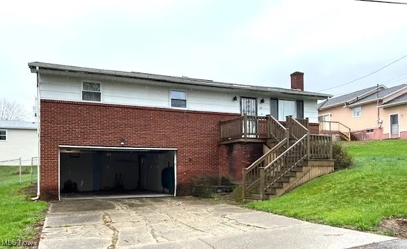 View of front of home with brick siding, a garage, driveway, a chimney, and a front lawn