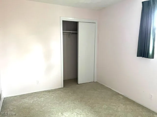 Unfurnished bedroom with light carpet and a closet