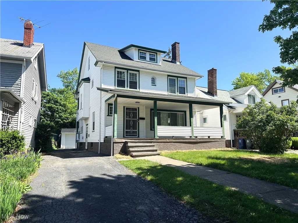 Traditional style home featuring a porch, a chimney, a detached garage, and central AC