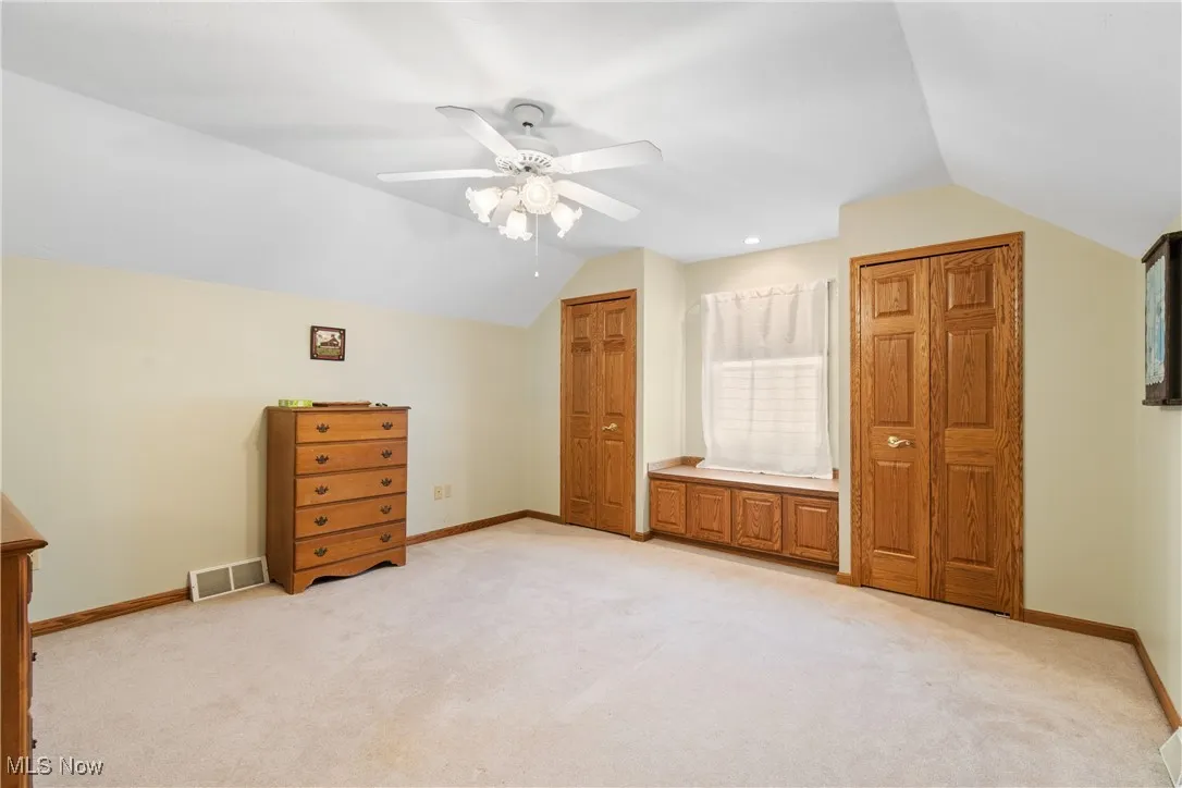 Additional living space with vaulted ceiling, light carpet, ceiling fan, and baseboards
