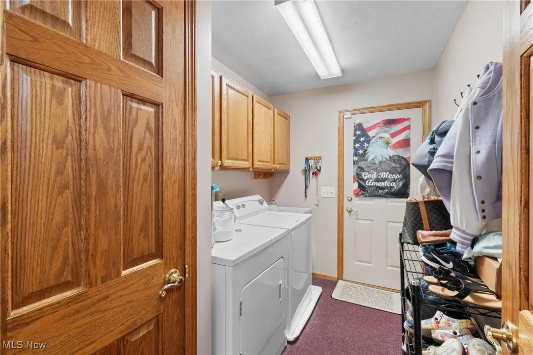 Laundry room with cabinet space, washing machine and clothes dryer, dark carpet, and baseboards