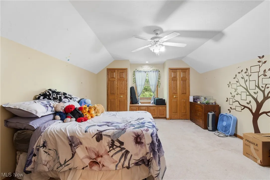 Bedroom with light colored carpet, lofted ceiling, and a ceiling fan