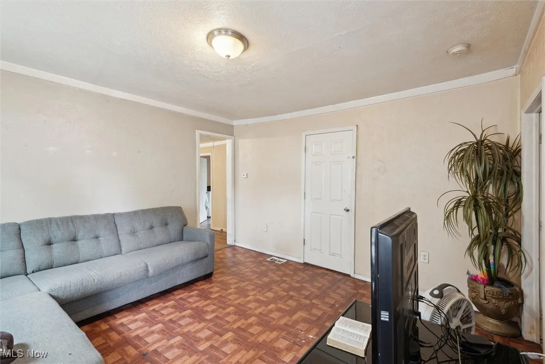 Living room with a textured ceiling and ornamental molding