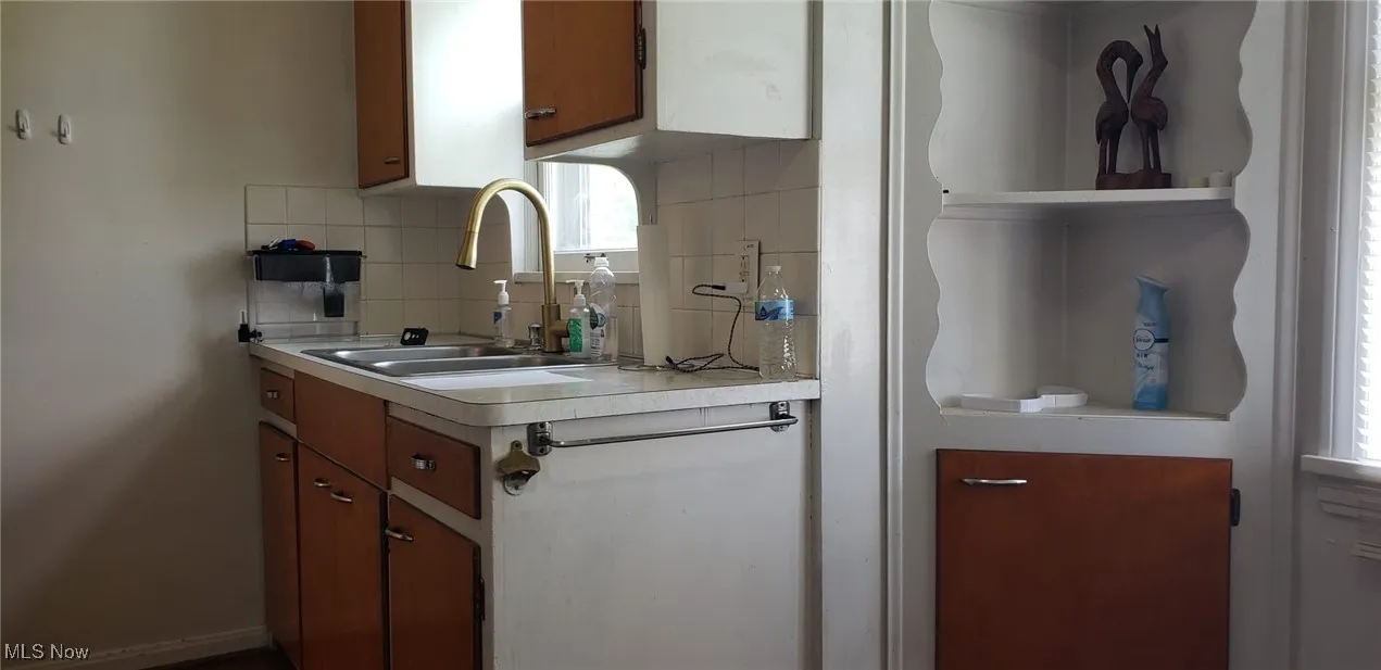 Kitchen featuring a sink, light countertops, tasteful backsplash, and brown cabinetry