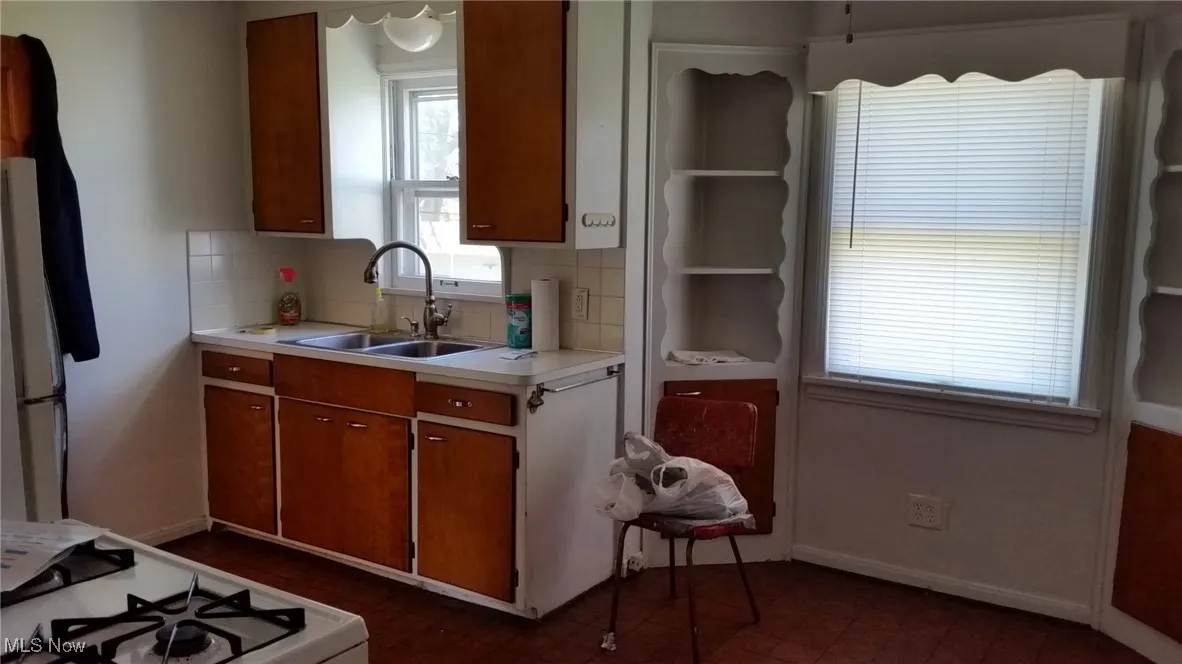 Kitchen with a sink, light countertops, decorative backsplash, and baseboards