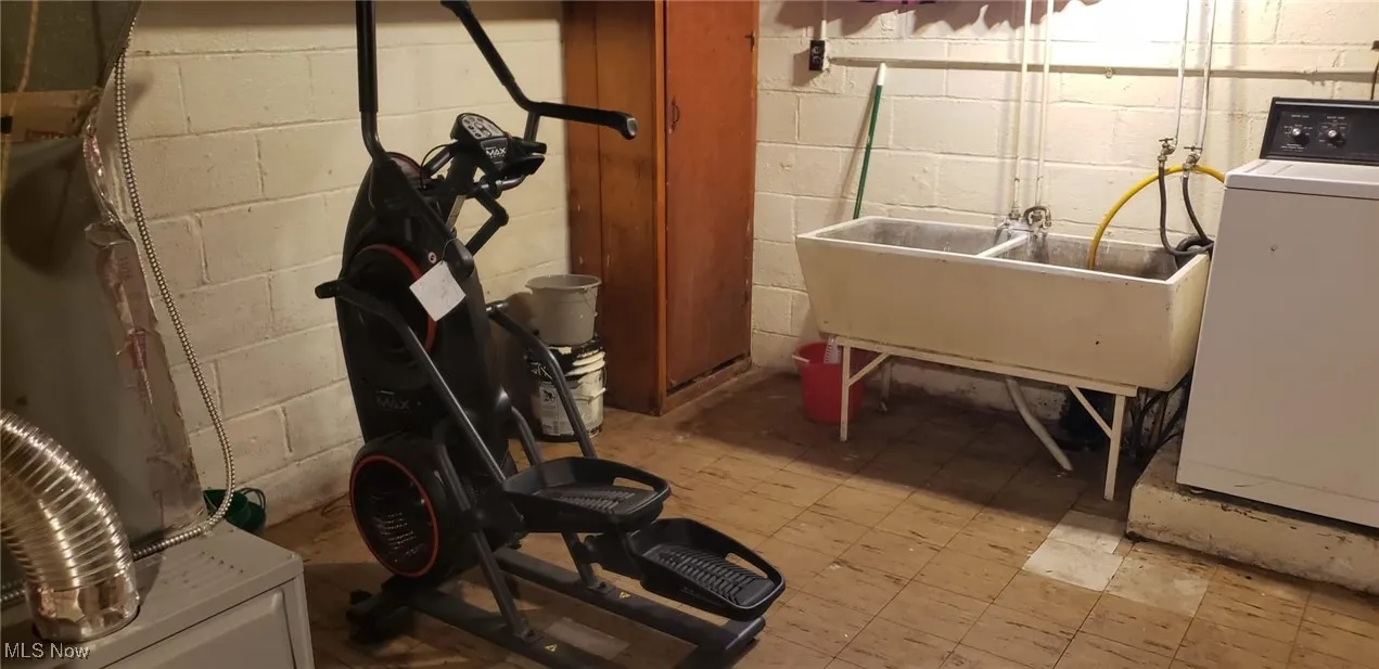 Miscellaneous room featuring washer / clothes dryer, concrete block wall, and a sink