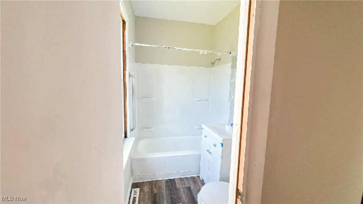 Full bath with wood finished floors, vanity, bathtub / shower combination, and toilet