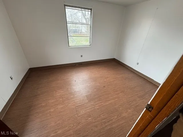 Spare room featuring wood finished floors and baseboards