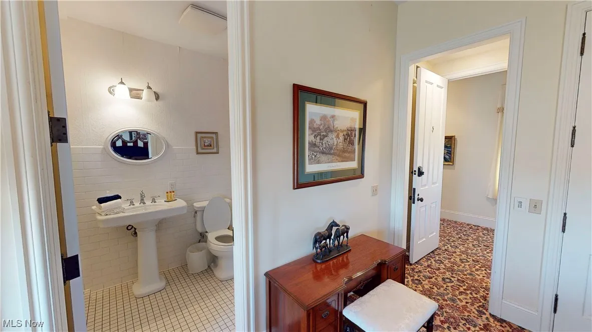 Bathroom featuring tile walls, toilet, and tile patterned floors
