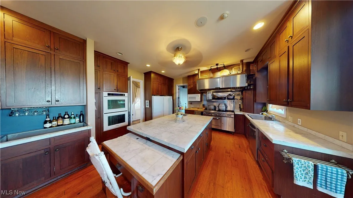 Kitchen featuring wood-type flooring, a center island, white appliances, and sink