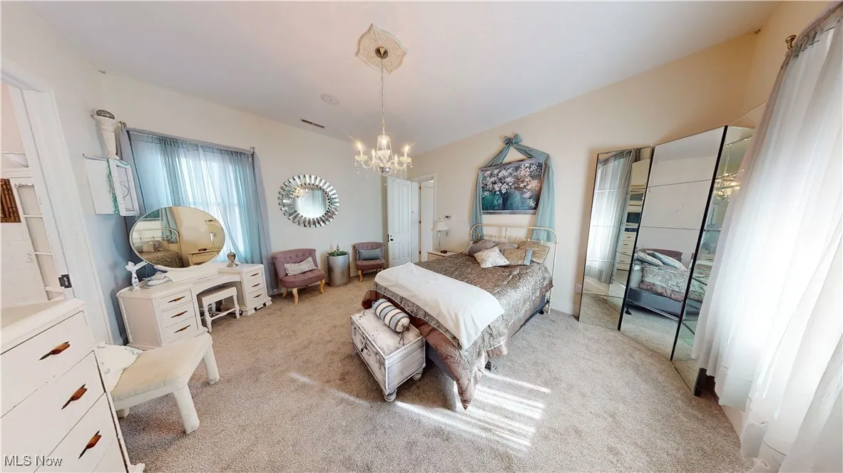 Bedroom featuring light colored carpet and a notable chandelier