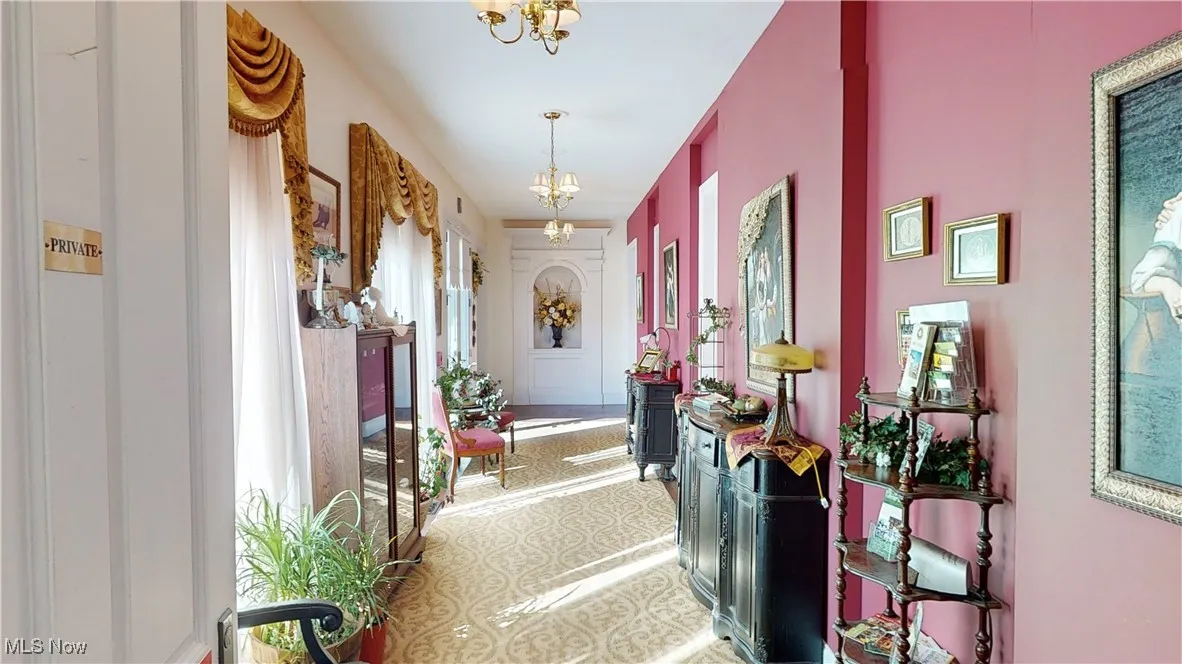 Hallway with a healthy amount of sunlight, an inviting chandelier, and tile patterned floors