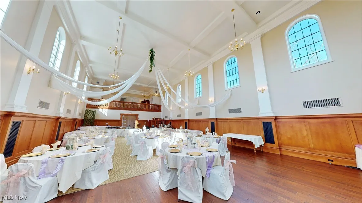 Dining area with dark wood-type flooring, an inviting chandelier, beamed ceiling, and high vaulted ceiling