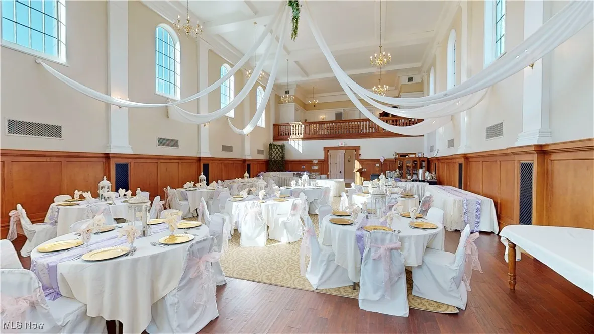 Dining space with a high ceiling, dark hardwood / wood-style floors, a notable chandelier, and beamed ceiling