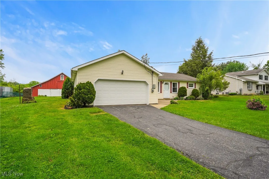 Ranch-style home with asphalt driveway, a front yard, and a garage