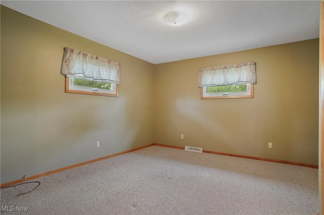 Carpeted empty room with baseboards