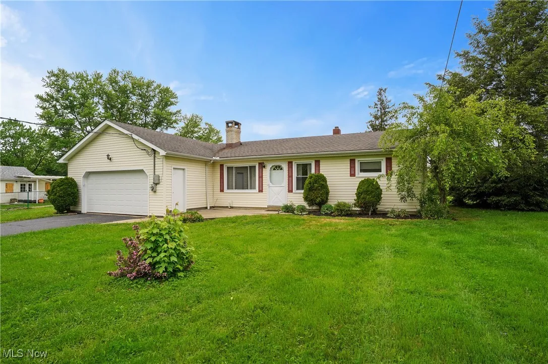 Ranch-style house with an attached garage, driveway, a chimney, and a front yard