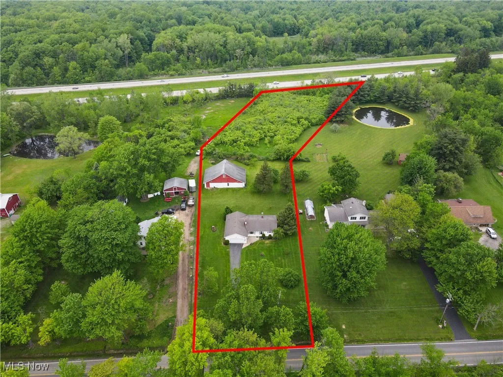 Aerial view of property's location featuring a nearby body of water, property boundaries highlighted, and a heavily wooded area