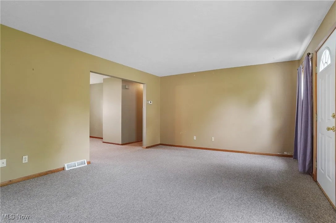 Unfurnished room featuring light colored carpet and baseboards