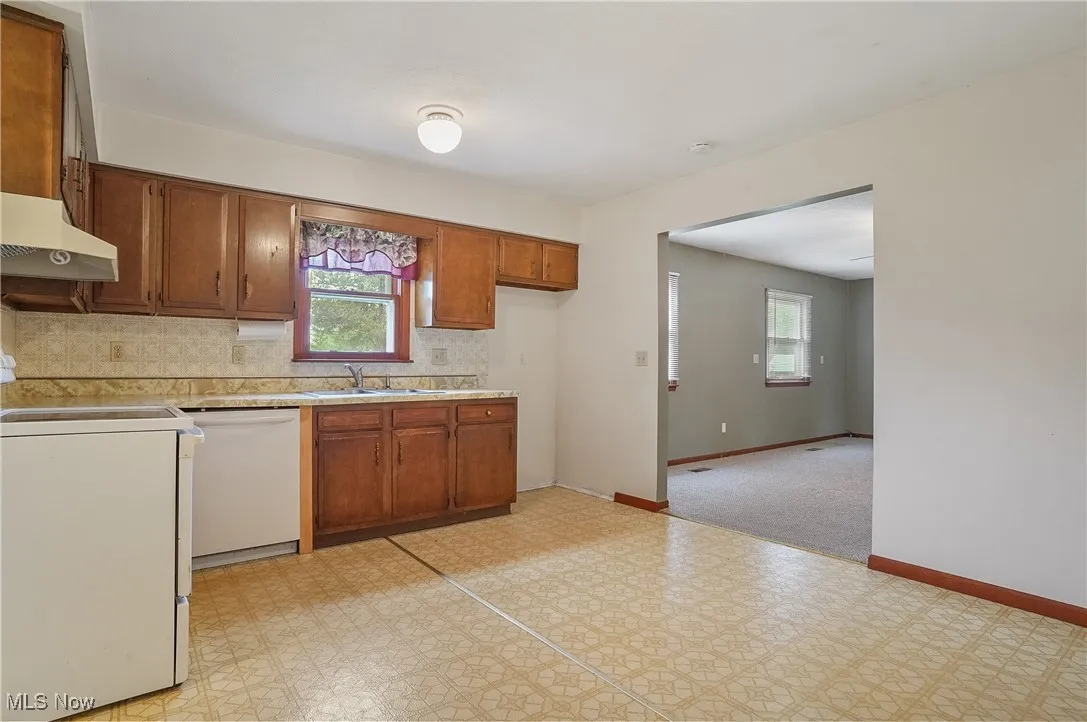 Kitchen with white dishwasher, stove, light flooring, light countertops, and healthy amount of natural light