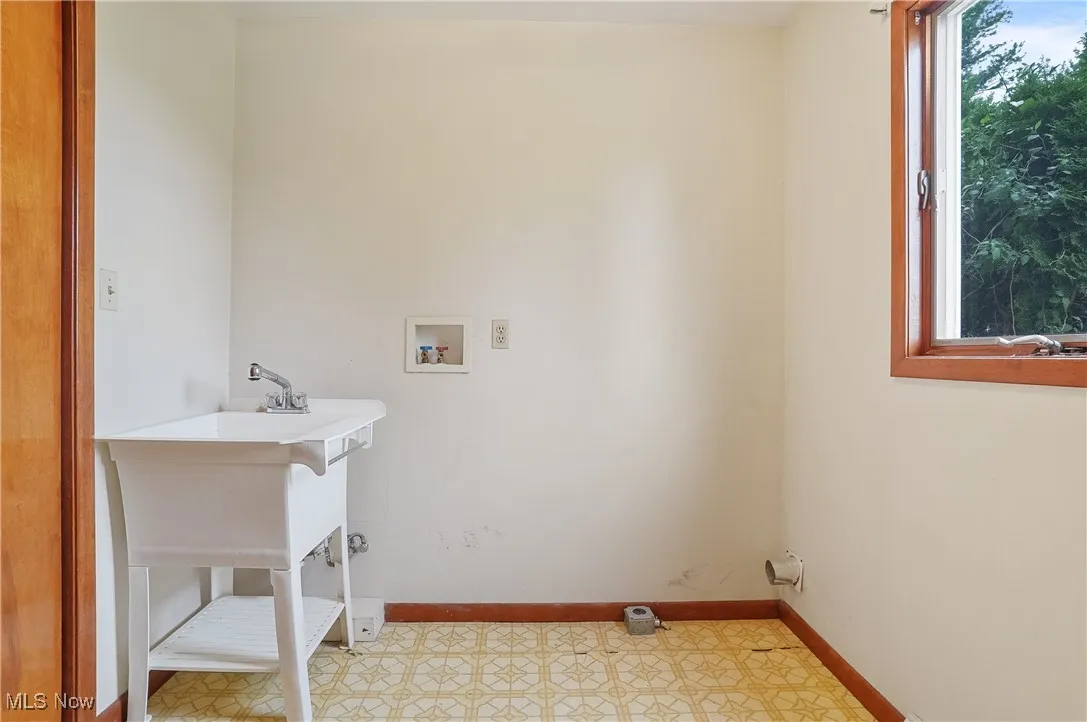 Laundry area with hookup for a washing machine, baseboards, and light floors