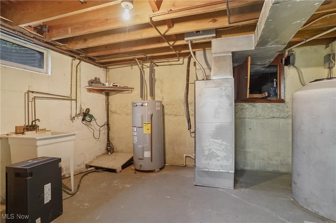 Unfinished below grade area featuring electric water heater and oil tank