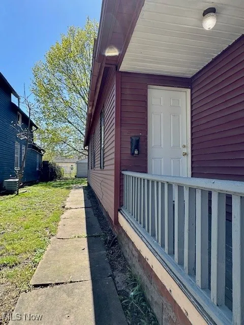 View of exterior entry featuring cooling unit and a yard