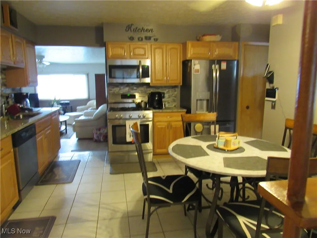 Kitchen with stainless steel appliances, tasteful backsplash, a sink, and light tile patterned floors