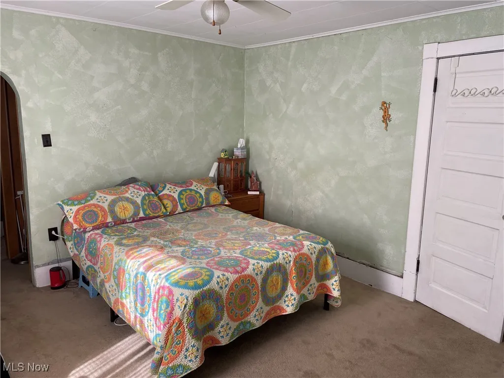 Bedroom featuring carpet floors, ceiling fan, and ornamental molding