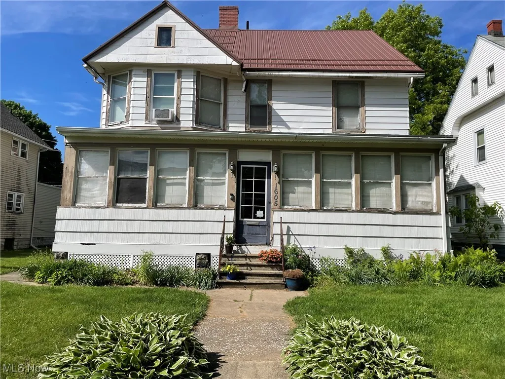View of front facade featuring a chimney, entry steps, metal roof, cooling unit, and a front yard