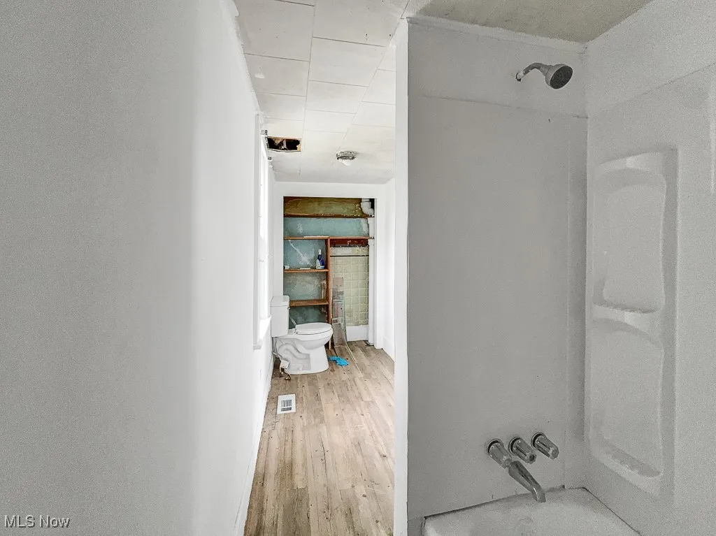 Bathroom with toilet, wood finished floors, a shower, and a paneled ceiling