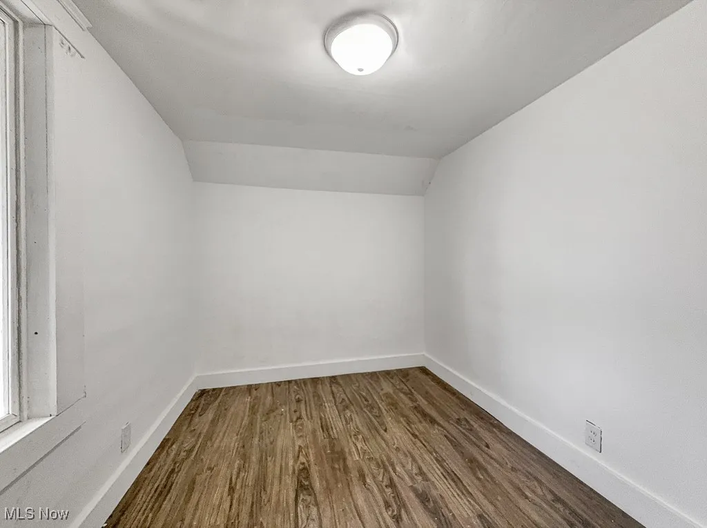 Bonus room with dark wood finished floors, lofted ceiling, and baseboards
