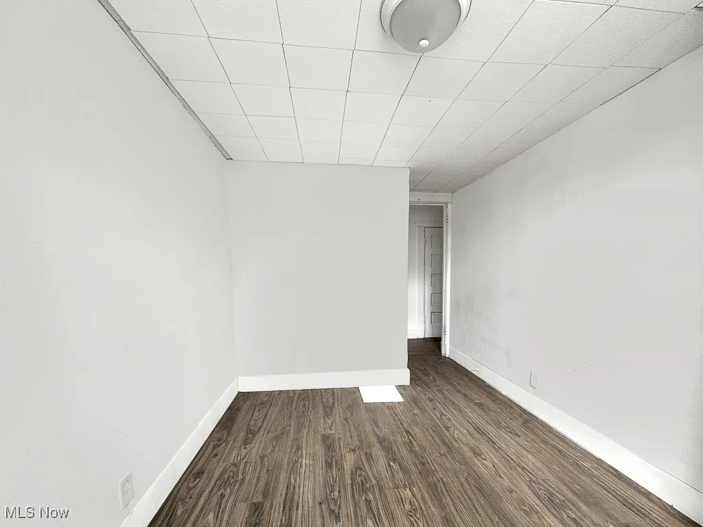 Empty room featuring dark wood-type flooring and baseboards