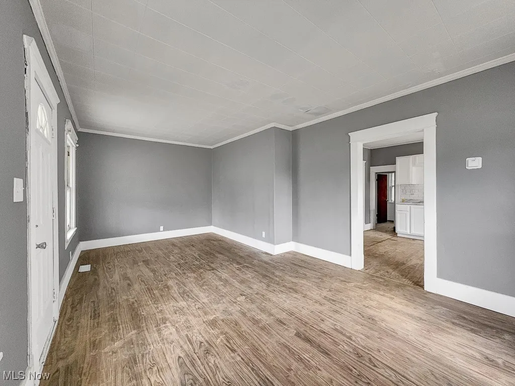 Empty room featuring ornamental molding, wood finished floors, and baseboards