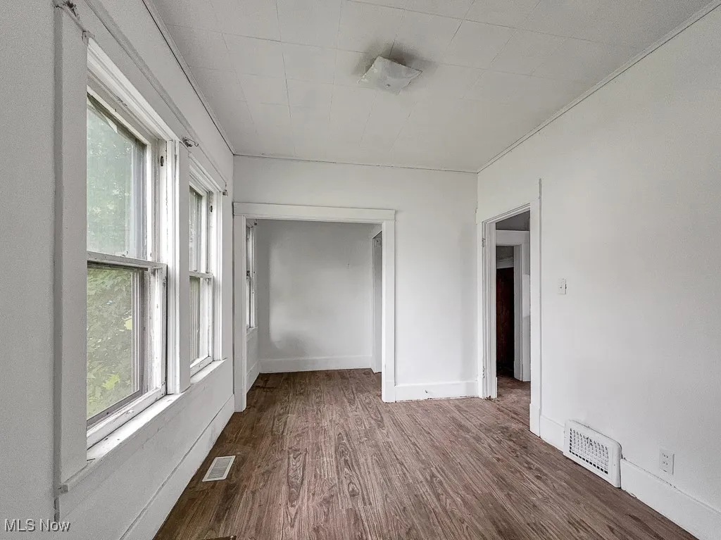 Empty room featuring dark wood-style flooring and baseboards
