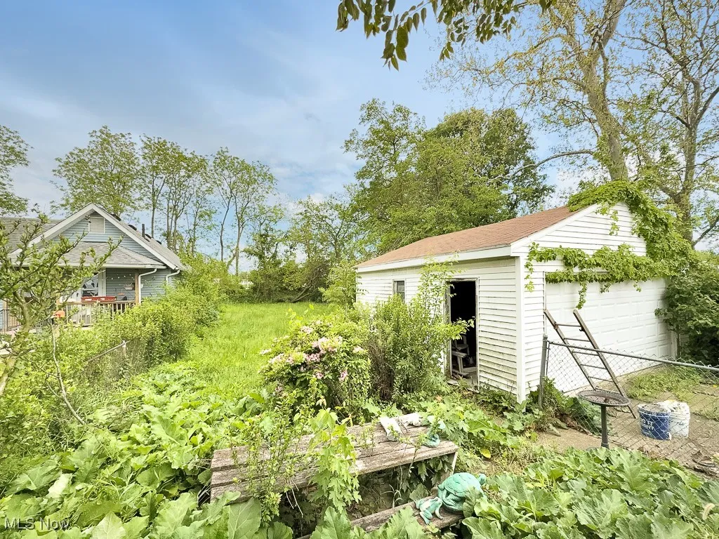 View of yard featuring a garage, an outdoor structure, and fence