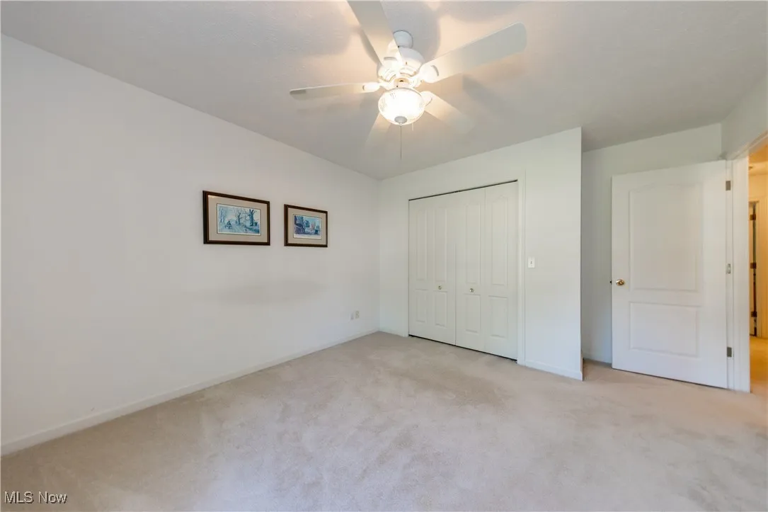Unfurnished bedroom with light colored carpet, a closet, baseboards, and a ceiling fan