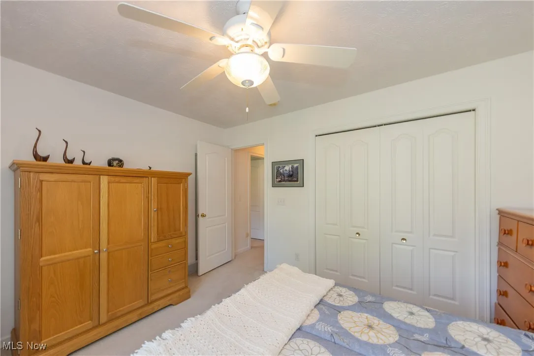 Bedroom with a closet, light carpet, and ceiling fan
