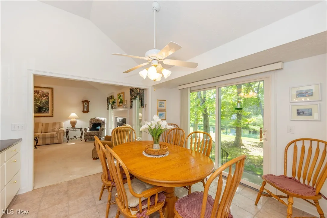 Dining space featuring light tile patterned floors, a ceiling fan, lofted ceiling, and light carpet