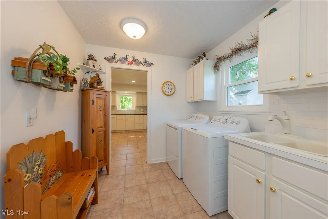 Laundry room with cabinet space, washing machine and dryer, plenty of natural light, and light tile patterned flooring