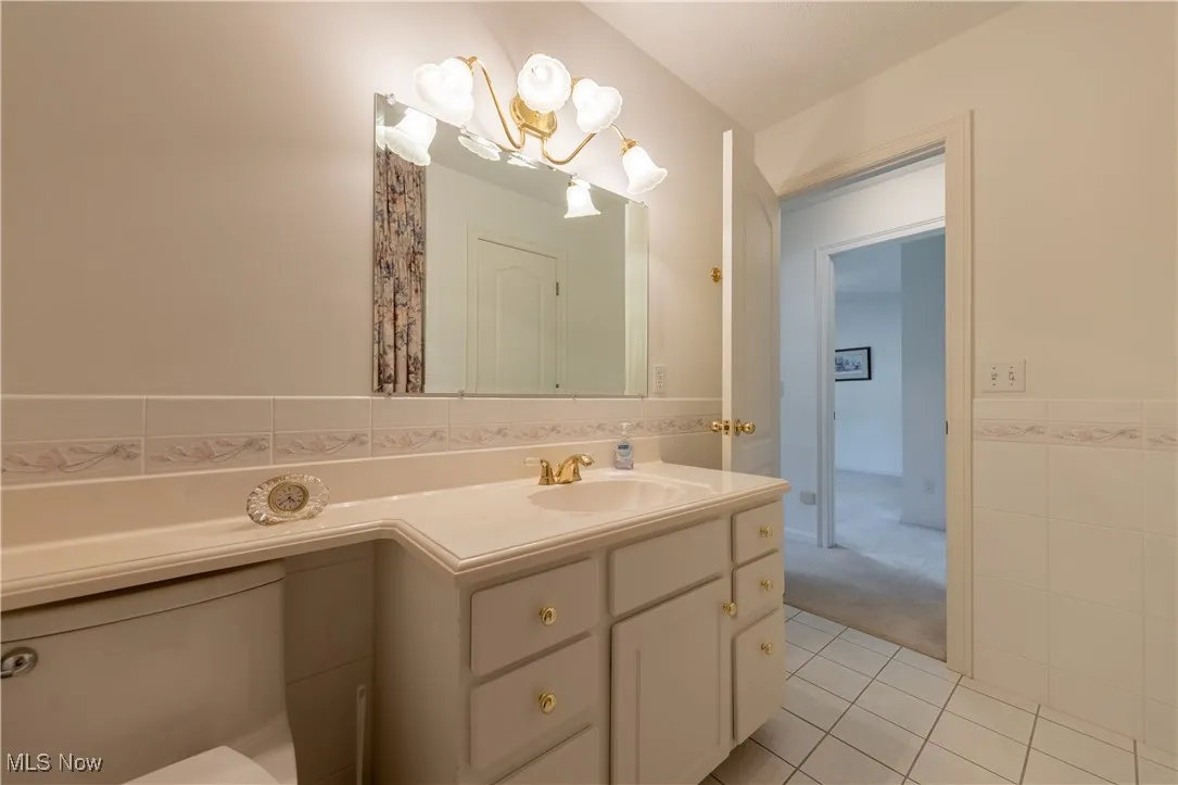 Bathroom with tile patterned flooring, tile walls, and vanity