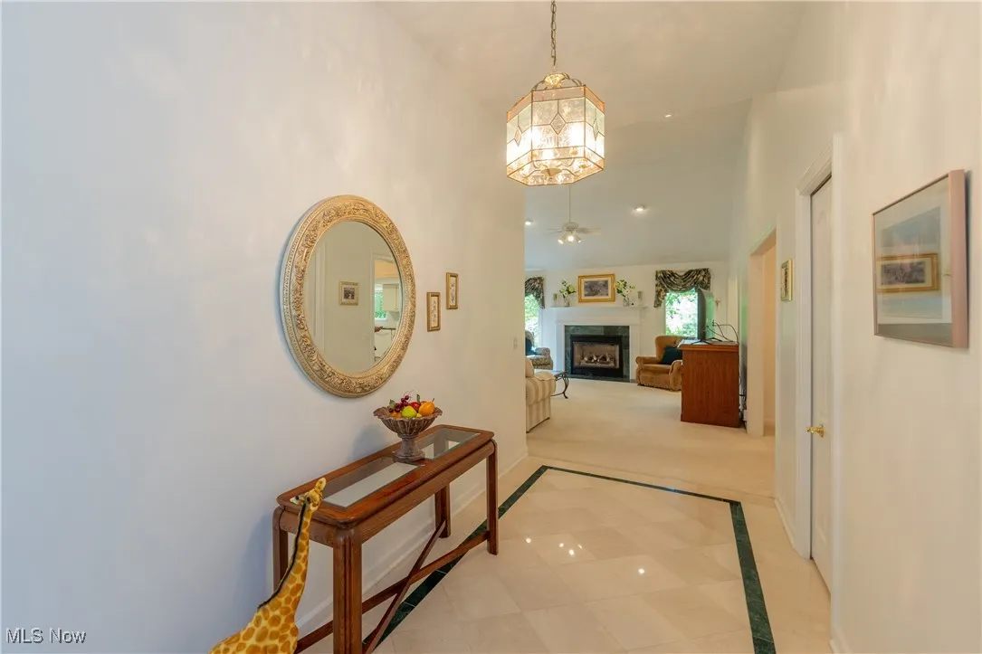 Corridor featuring baseboards, light carpet, and a high ceiling