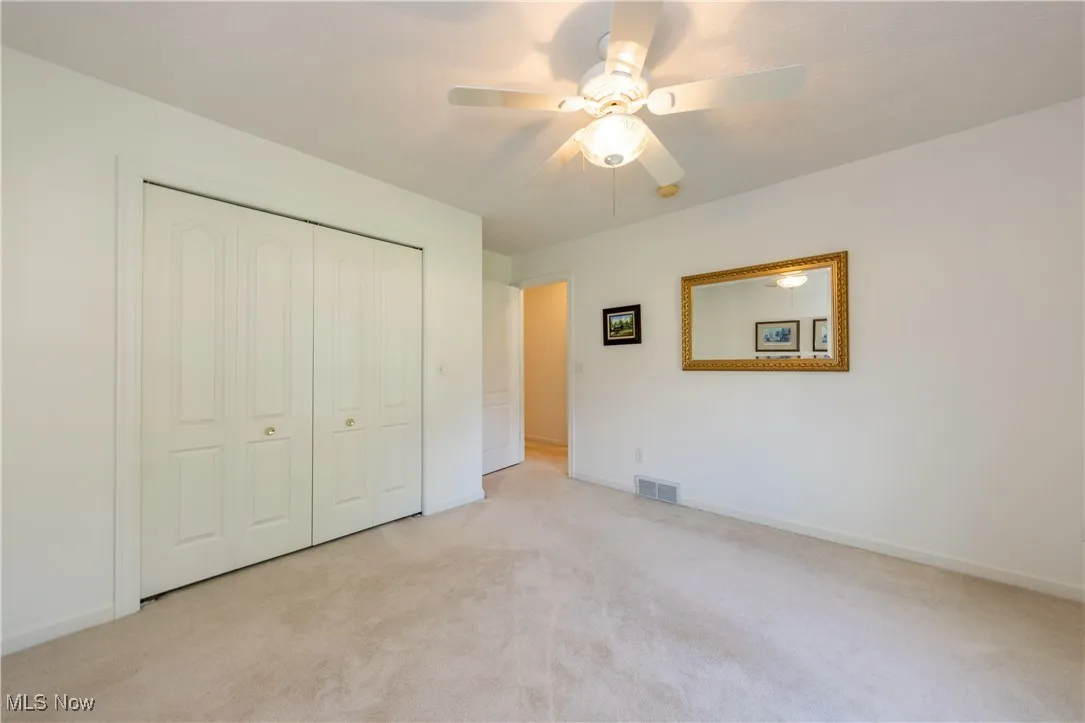 Unfurnished bedroom featuring light colored carpet, a closet, baseboards, and a ceiling fan