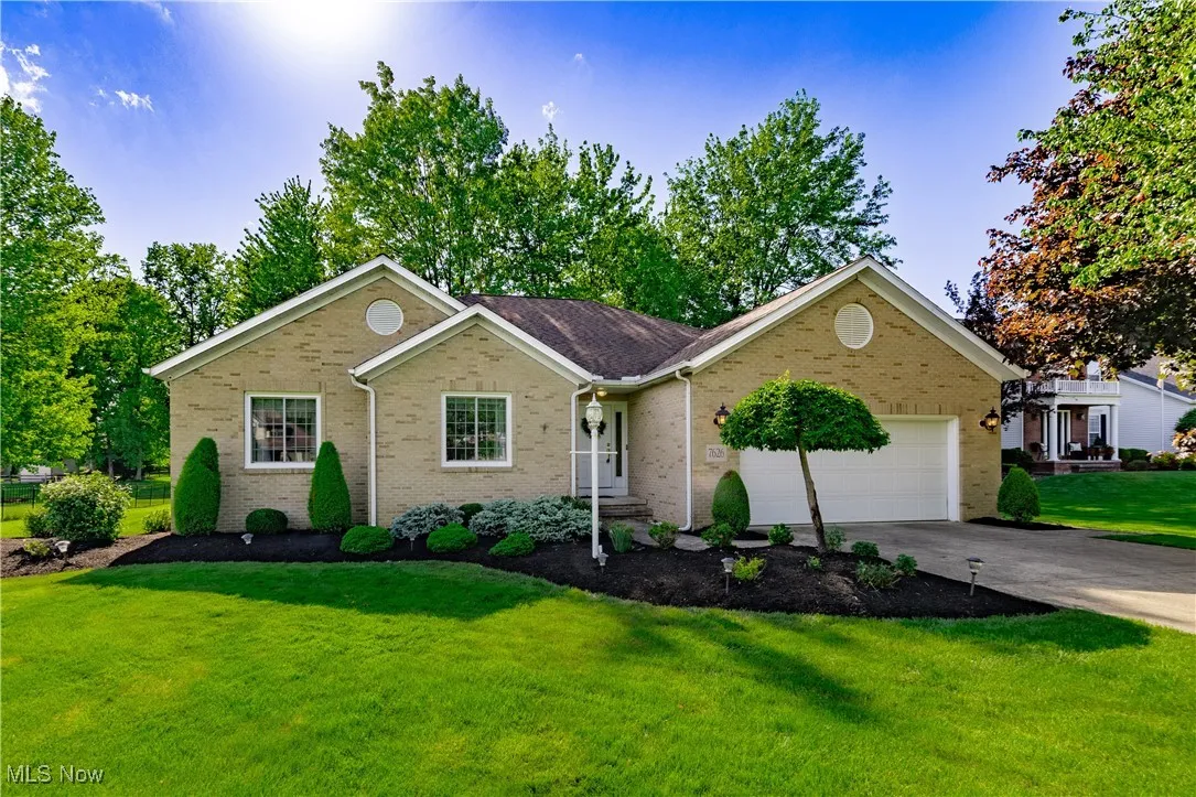 Single story home featuring brick siding, an attached garage, a front yard, and driveway