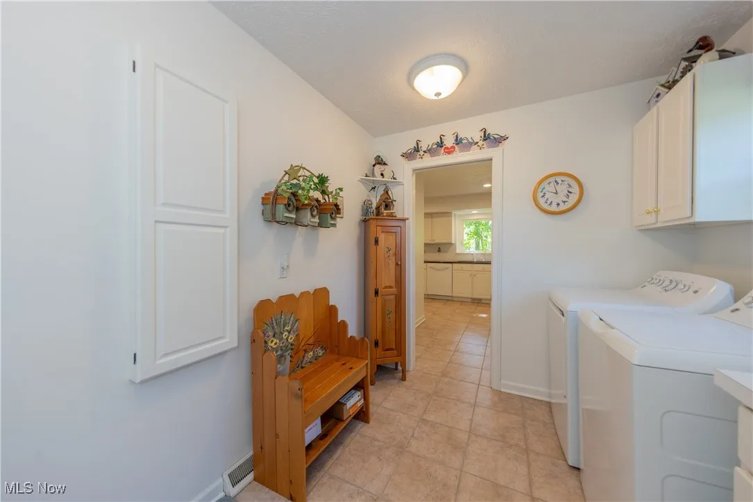 Clothes washing area featuring cabinet space, independent washer and dryer, baseboards, and light tile patterned floors