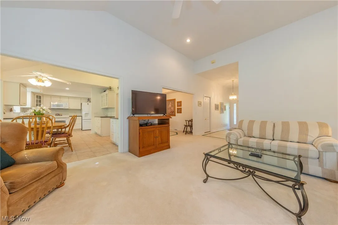 Living room featuring ceiling fan, high vaulted ceiling, light carpet, recessed lighting, and baseboards